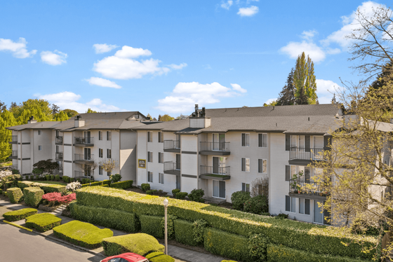 Charming apartment complex surrounded by lush greenery and vibrant landscaping under a clear blue sky.