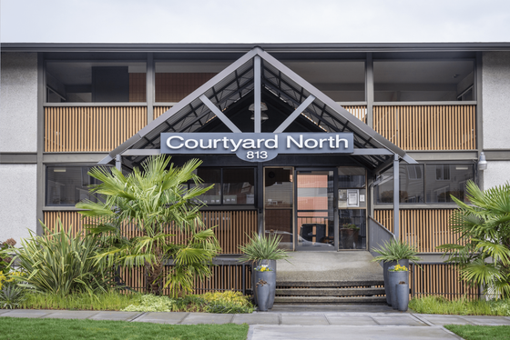 Inviting entrance of Courtyard North with modern architectural design, lush greenery, and welcoming atmosphere.