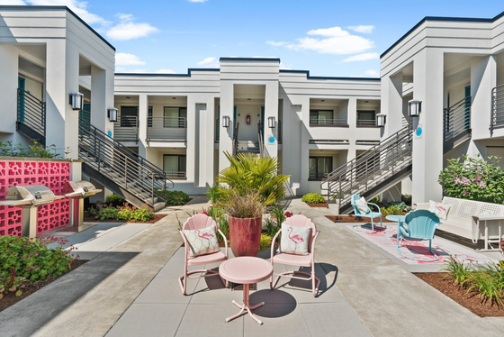 Charming apartment courtyard with vibrant seating, lush greenery, and modern architectural design, perfect for relaxing and enjoying the outdoors.