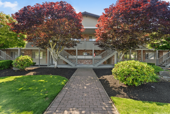 Charming apartment exterior featuring vibrant red trees, manicured lawns, and inviting entrance pathways.