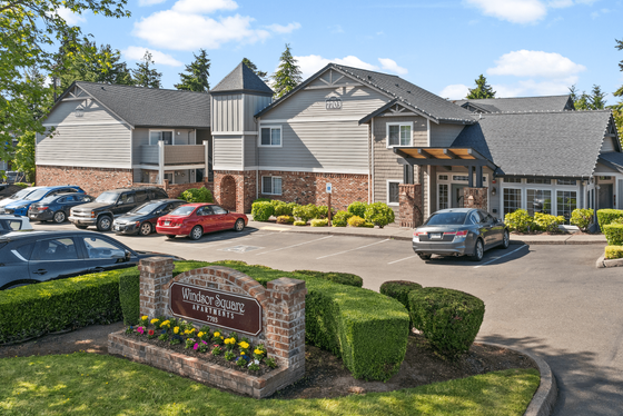 Charming Windsor Square Apartments exterior showcasing beautifully manicured landscaping, ample parking, and a welcoming facade under a vibrant blue sky.
