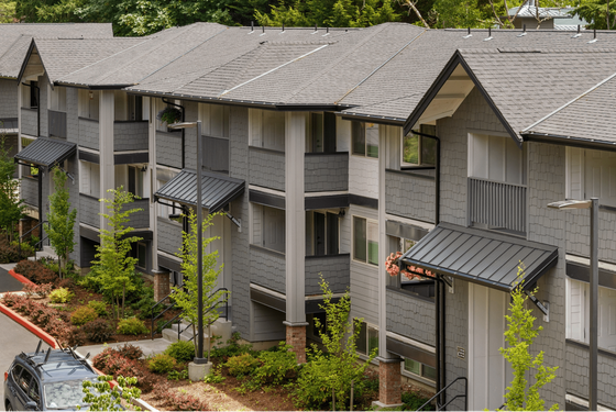 Charming apartment complex nestled in lush greenery with modern gray facade and inviting entryways.