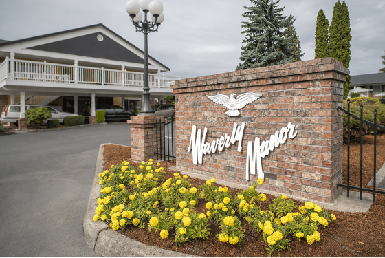 Charming entrance of Waverly Manor with lush landscaping and elegant brickwork, creating a welcoming atmosphere.