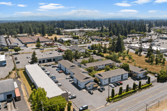 Stunning aerial view of modern apartment complex surrounded by lush greenery, showcasing a vibrant community setting under clear blue skies.