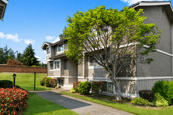 Charming two-story apartment building surrounded by lush greenery and a well-maintained garden, perfect for tranquil living.