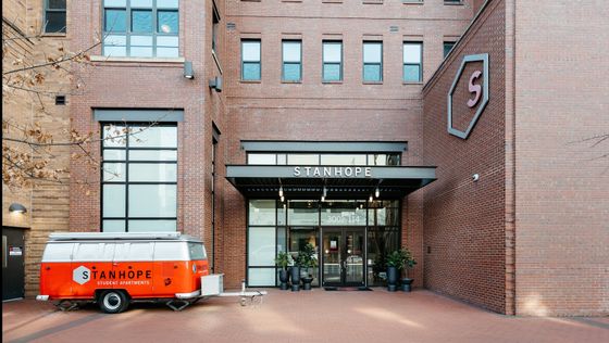 Chic urban entrance of Stanhope Student Apartments with red brick facade and a retro-style branded van.