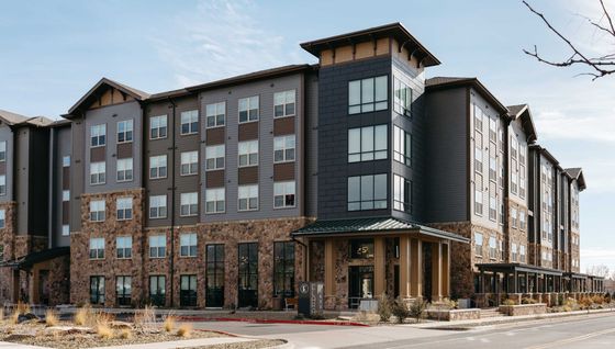 Chic modern apartment building featuring stone and wood design with expansive windows and inviting entryway.