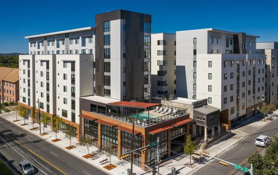 Modern apartment complex showcasing sleek architecture with a rooftop pool and urban surroundings.
