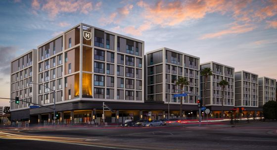 Modern urban apartment complex under a stunning sunset, featuring sleek architecture and vibrant city life.