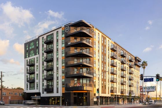 Modern apartment building with sleek design, spacious balconies, and vibrant urban appeal, set against a sunny sky.