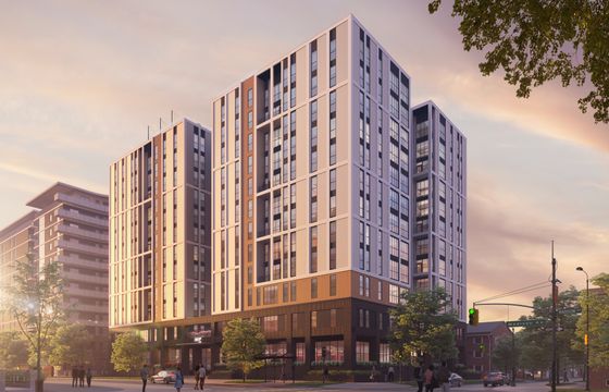Modern high-rise apartment building with sleek design, featuring large windows and sunset reflections, situated on a vibrant city street corner.