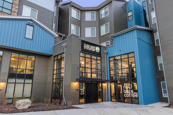 Contemporary apartment complex featuring stylish architecture with large windows and vibrant blue accents, highlighting the welcoming HUB entrance.