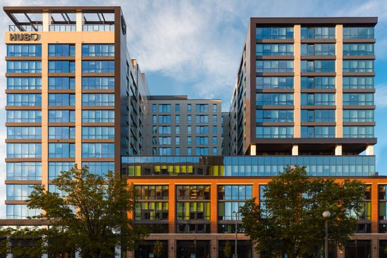 Modern urban apartment complex with sleek glass facade and contemporary design, reflecting vibrant city living.