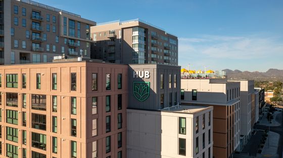 Modern urban apartment complex with stunning mountain views and rooftop amenities under clear blue skies.