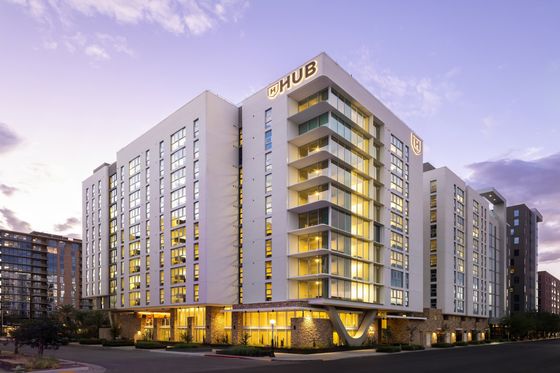 Modern high-rise apartment building with elegant architectural design and illuminated windows at sunset.