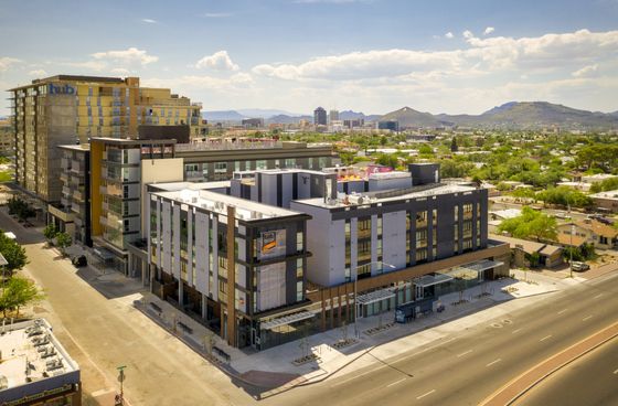 Modern urban apartment complex with stylish architecture, set against a stunning cityscape and mountain backdrop.