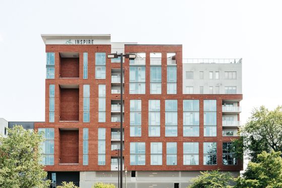 Modern urban apartment building with striking red brick facade and large windows, offering a stylish and inspiring living space.