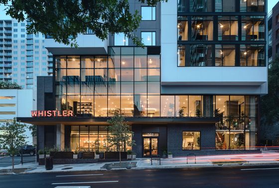 Modern apartment building with expansive glass facade and vibrant interior lighting, prominently featuring 'Whistler' signage.