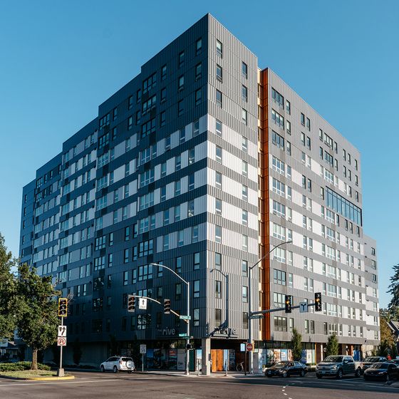 Modern urban apartment building with sleek design, ample windows, and vibrant cityscape surroundings.