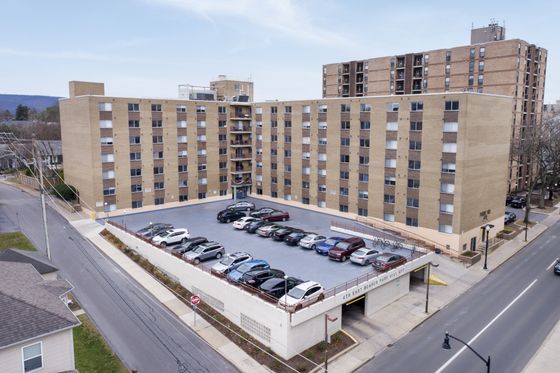 Modern apartment building with ample parking, located in a vibrant urban setting, offering convenient access and a welcoming facade.