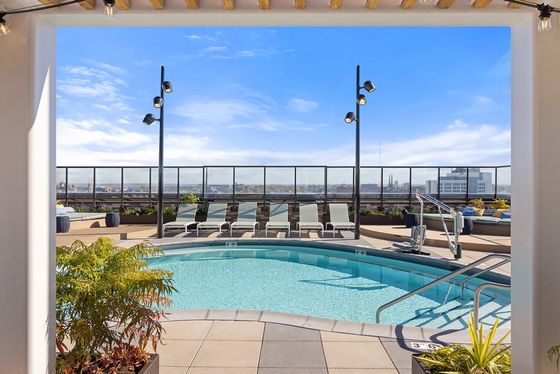 Luxurious rooftop pool area with sleek lounge chairs, stunning city views, and vibrant blue sky, perfect for relaxation and leisure.