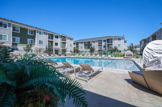 Luxurious apartment community with a pristine outdoor pool, surrounded by modern architecture and lush greenery, offering a perfect retreat for relaxation.