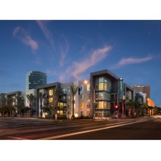 Exterior corner shot of AMLI Uptown Orange at sunset.  Interior lights are on throughout creating a glow.