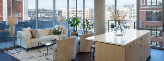 Interior daytime shot of kitchen and living room wihth floor to ceiling windows.