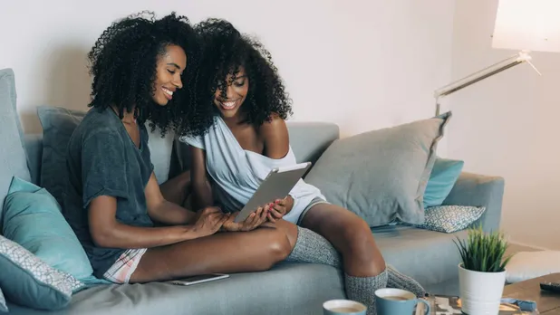 two women looking at devise on couch in apartment