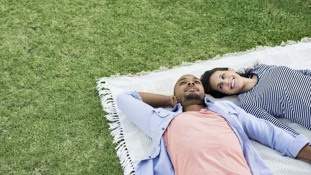 woman and man lying on blanket on green grass
