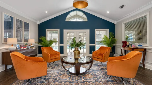 Stylish lounge with orange chairs, decorative plants, and a glass coffee table in a modern room.