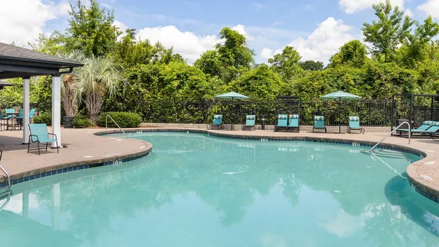 exterior pool with furniture and trees on sunny day
