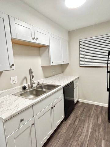 Contemporary kitchen with white cabinetry, marble countertops, and stainless steel sink.
