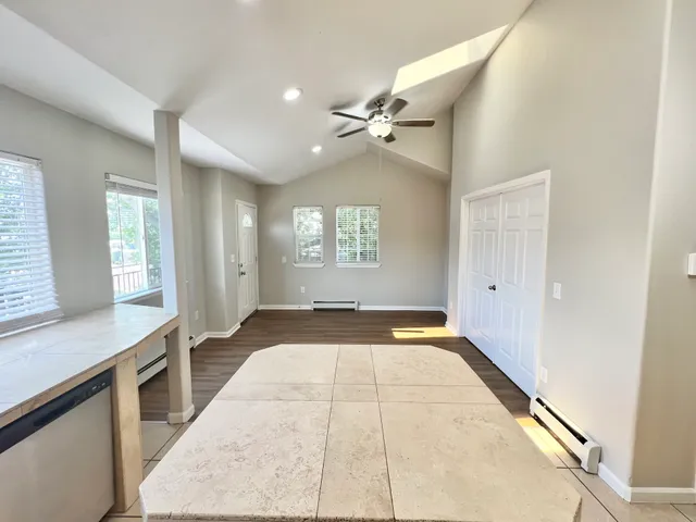 Open-concept living space with tiled flooring, large windows, and ceiling fan, offering ample natural light.