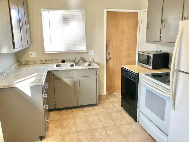 Modern kitchen with sleek gray cabinets, granite countertops, and essential appliances.