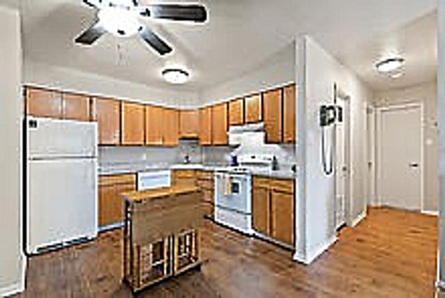 Bright, modern kitchen with wooden cabinets, white appliances, and an island counter.