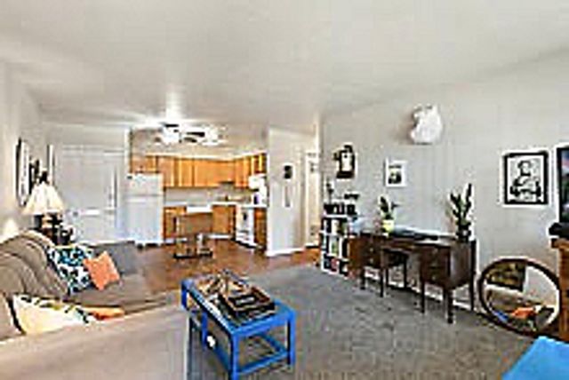 Inviting living room with comfortable seating and an open-concept kitchen, featuring modern decor.