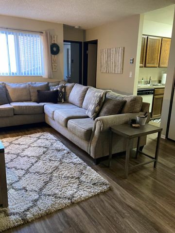 Inviting living room with a plush L-shaped sofa, warm lighting, and adjoining kitchen area.