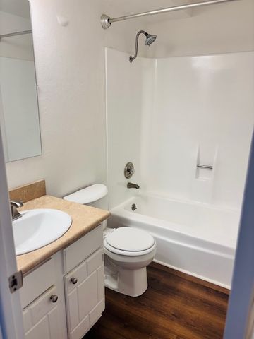 Bright and modern bathroom with sleek white fixtures and wood-style flooring.
