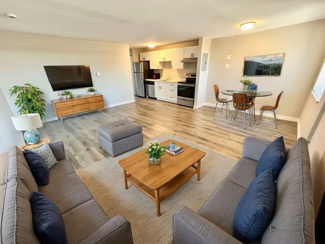 Modern living room with stylish furnishings, open kitchen, cozy dining area, and wooden flooring, perfect for comfortable and elegant living.