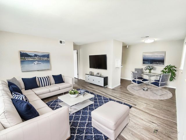 Chic living room with plush white sofas, blue accent pillows, modern decor, and a stylish dining area.