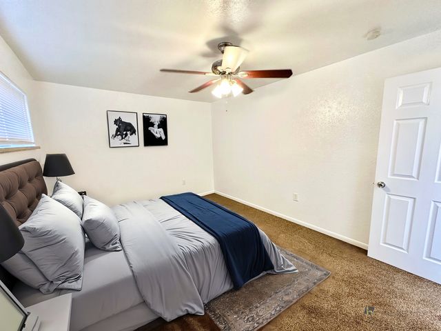 Inviting bedroom with plush pillows, modern art, and elegant ceiling fan.