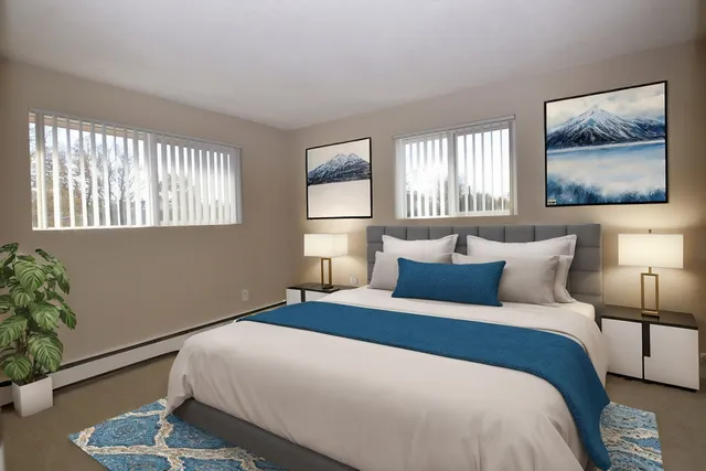 Elegant bedroom with a modern interior, featuring a plush bed with blue accents, stylish artwork, and large windows for natural light.