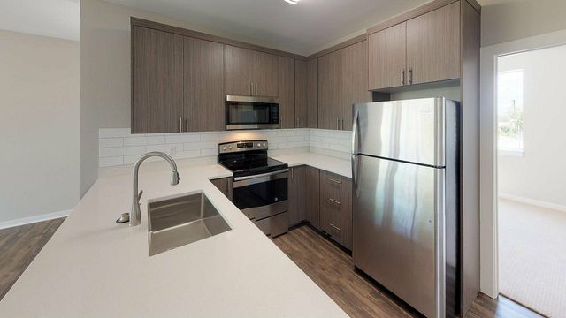 Modern kitchen with sleek stainless steel appliances, stylish wood cabinetry, and a granite countertop with an integrated sink.