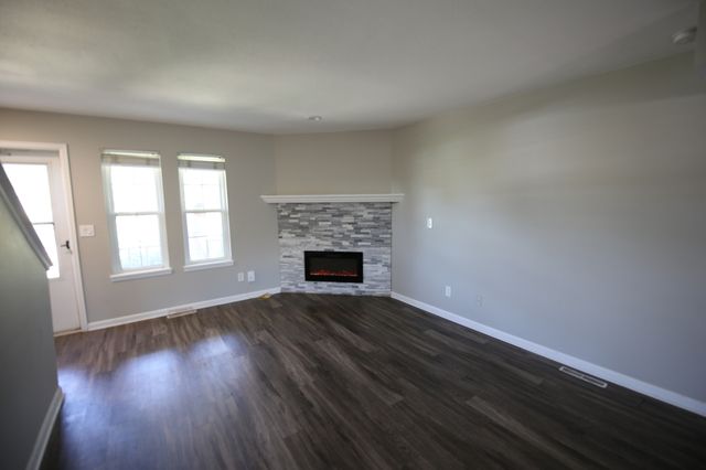 Charming living room with elegant laminate flooring, large windows for natural light, and a cozy modern fireplace.