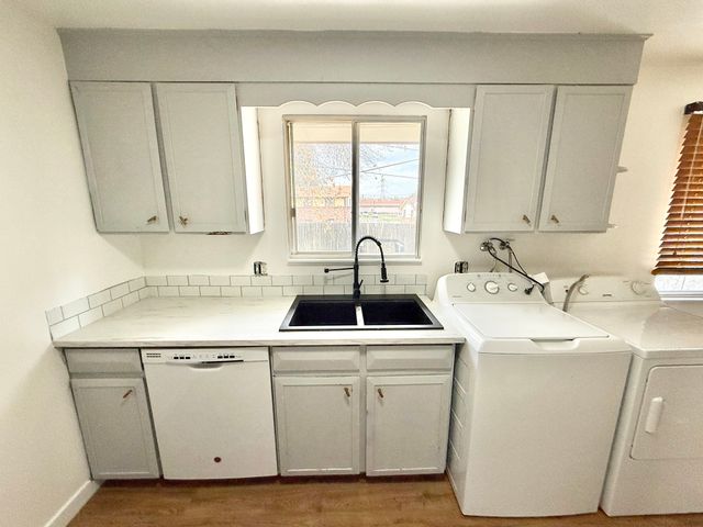 Bright and modern kitchen featuring sleek cabinetry, convenient dishwasher, and an integrated laundry area with washer and dryer.