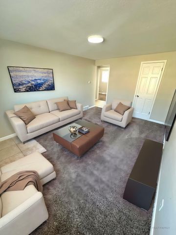 Inviting living room with plush carpeting, elegant beige seating, and modern decor, perfect for relaxation and entertainment.