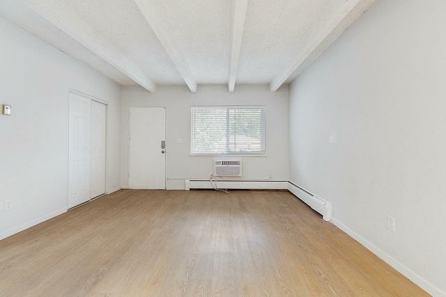 Bright and spacious living room with elegant wooden flooring, large window, and minimalistic white walls.