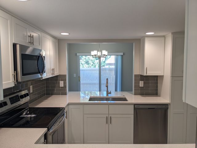 Modern kitchen with sleek white cabinets, stainless steel appliances, and elegant subway tile backsplash, creating a bright and inviting space.