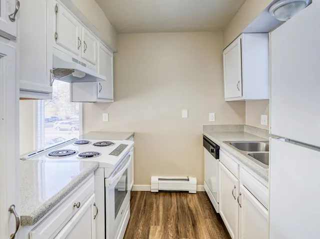 Bright, modern kitchen with white cabinetry, sleek countertops, and hardwood flooring.